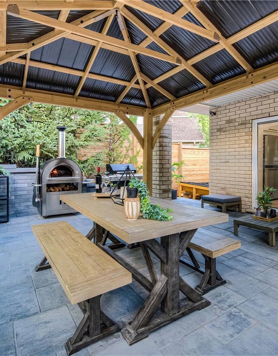 Covered outdoor pavilion with pizza oven, dining table and natural stone patio